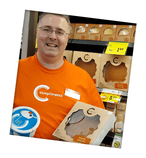 Steve Enns of St. Rose IGA in front of shelves of desserts in store and holds a pumpkin pie.