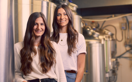 Taylor and Colleen smiling to camera, standing in their brewery.