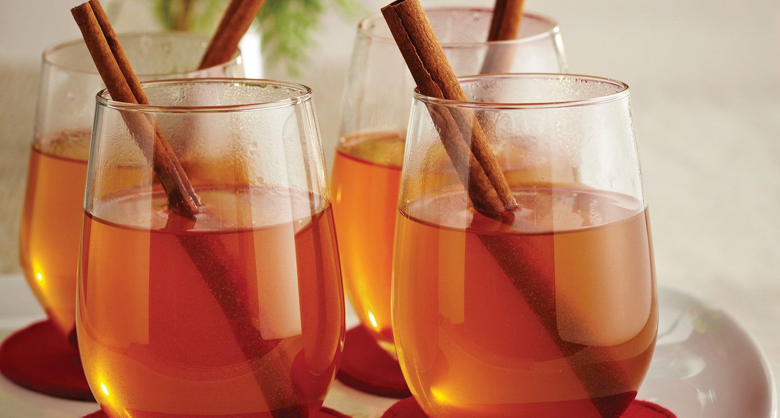 two glasses of mulled cider with cinnamon sticks