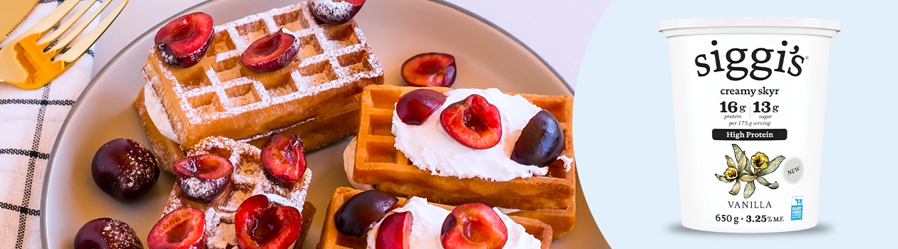 Freshly made waffles topped with pitted cherries cut in half.